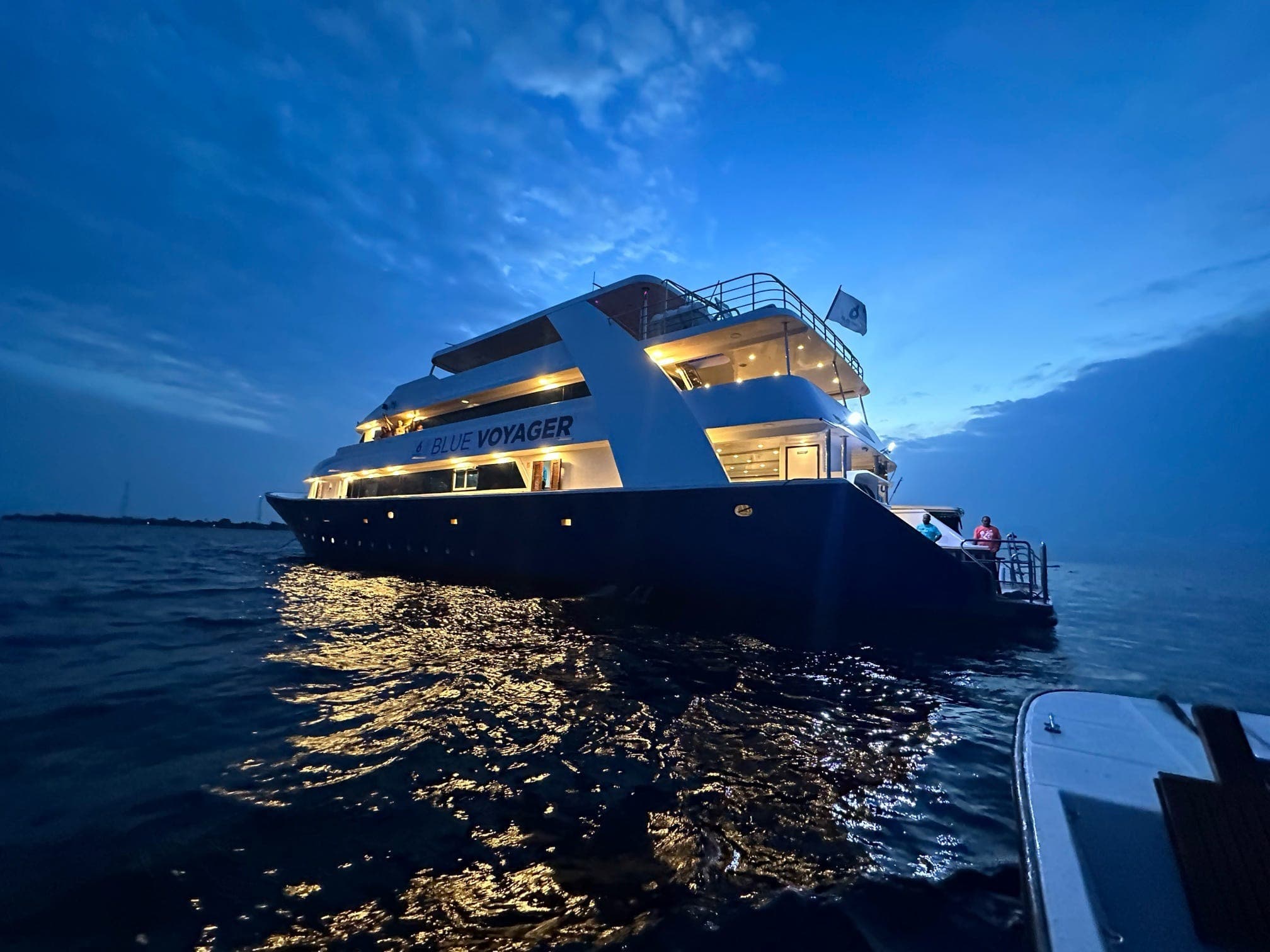 The Blue Voyager liveaboard lit up at dusk at anchor in the Maldives